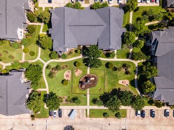 A bird's eye view of a neighborhood with houses, cars, and a park.